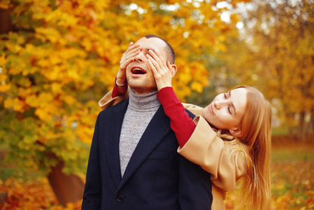 s eyes to make a surprise. Couple enjoying a beautiful autumn da