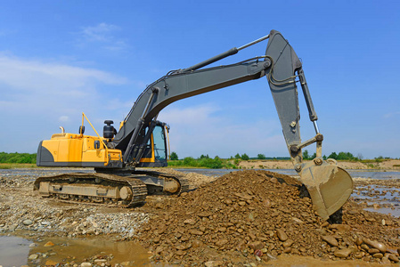 后方自卸货车抽取和装载在河流主流挖掘的砾石照片