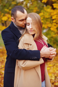 女孩和男人或情人约会拥抱。 在公园里相爱的夫妇。 秋天约会的概念。 在自然背景上有着快乐面孔的男人和女人。 恋爱中的年轻夫妇在秋