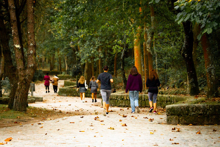 路过的人回头看各种人在公园里散步,一个女跑步者路过.照片