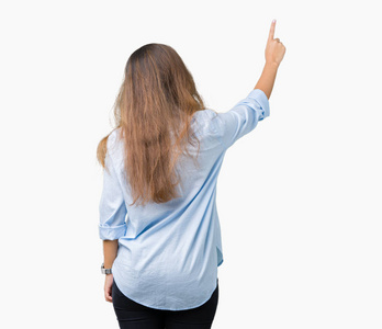 年轻漂亮的深褐色头发的商务女性，在孤立的背景下摆姿势，向后指着后面的手指