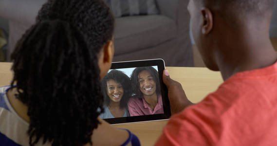 年轻的黑人夫妇通过平板电脑视频聊天与朋友交谈
