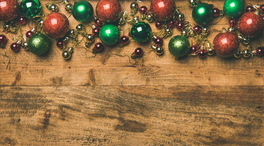 圣诞节新年假期背景纹理壁纸。 平躺着五颜六色的绿色红色金色的圣诞树装饰球在木制背景上的顶部视图复制空间。 新年贺卡