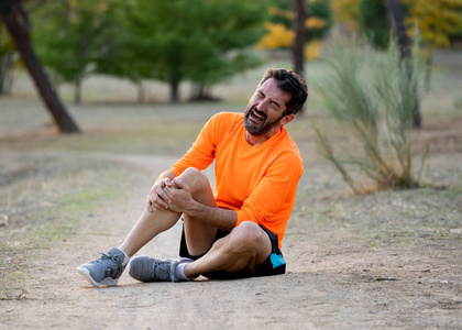 骨折后年轻的健身男子抱着膝盖,双手疼痛后,肌肉损伤,骨折,腿部疼痛