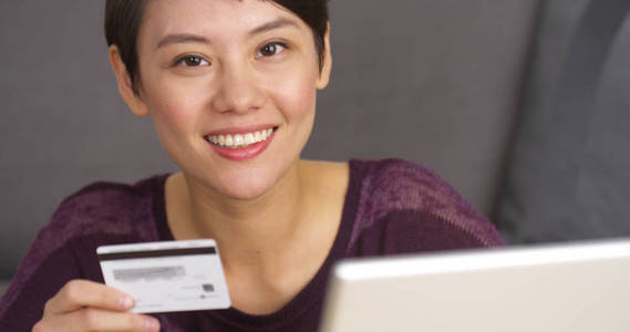 快乐可爱的亚洲女人拿着信用卡