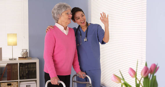 幸福的老年妇女病人与亚洲护士交谈
