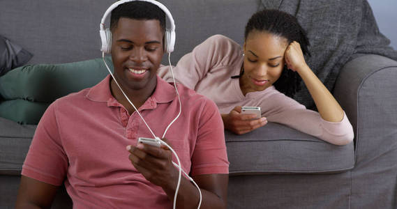 年轻的黑人夫妇听音乐，用智能手机拍照。
