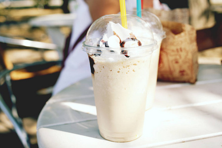大份咖啡拿铁的特写，白天在公园的桌子上放着奶油和巧克力