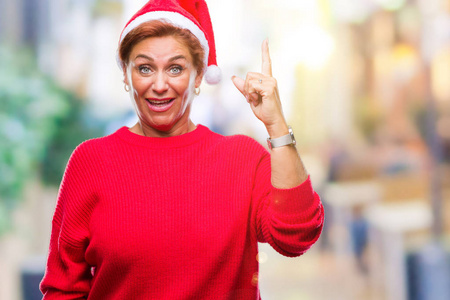 具有吸引力的高级白种人红发妇女戴着圣诞帽，在孤立的背景上指点着成功的想法。 退出并快乐。 一号。