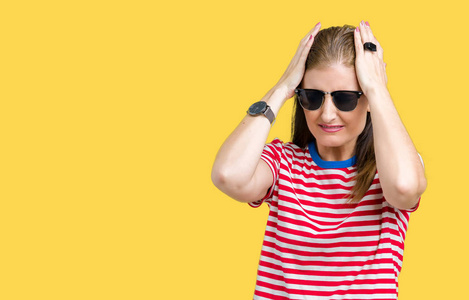 中年成熟的女人戴着太阳镜，在孤立的背景下患有头痛，绝望和压力，因为疼痛和偏头痛。 手放在头上。