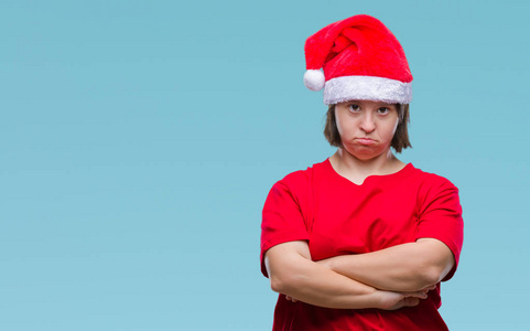 患有唐氏综合症的年轻成年女性戴着圣诞帽，在孤立的背景怀疑和紧张，不赞成的表情在脸上交叉的手臂。消极的人。