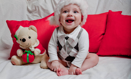 一个戴红帽子的小孩吃饼干和牛奶。一个戴红帽子的婴儿的圣诞摄影。新年假期和圣诞节。