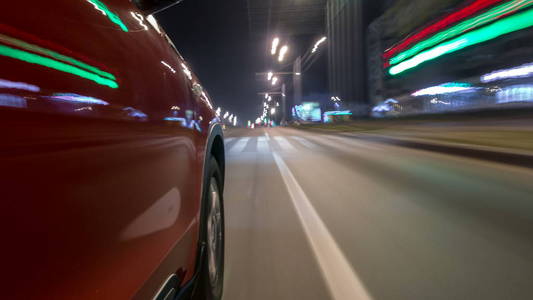 从快速驾驶的汽车在一条城市时间推移超移路的夜间大道上的快速行驶的城市外观，车上的灯高速反射。 现代城市的快速节奏。
