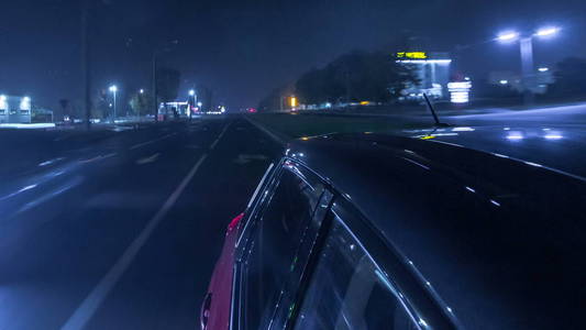 从快速驾驶的汽车在一条城市时间推移超移路的夜间大道上的快速行驶的城市外观，车上的灯高速反射。 现代城市的快速节奏。