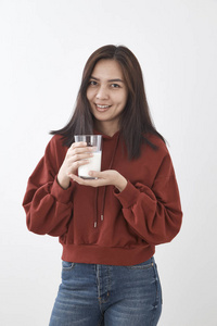 美丽的年轻亚洲女人喝牛奶白色的墙壁背景