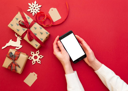 s hands holding phone on red background with Christmas decoratio