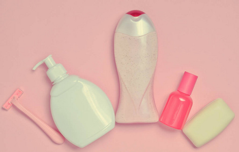 一瓶芳香香水洗发水肥皂剃须刀。 产品用于护理身体头发和个人卫生的粉红色粉彩背景。 上面的风景。 极简主义的趋势。 平躺着。