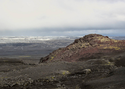 在冰岛中央高地vatnajokull国家公园欧洲的背景kverkfjoll偏远地区，红色火山石山上覆盖着绿色苔藓和融化的冰川。