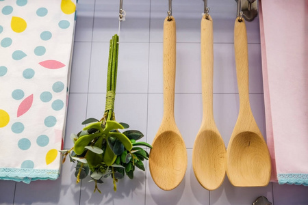 厨房柜台的视图与切割板挂在墙上几个有用的设备。 煎锅用铲子。 一个勺子和一个大勺子。 有粮食盖的玻璃瓶
