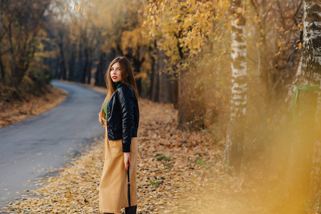 舒适时尚的年轻女孩独自走在秋天五彩缤纷的公园里