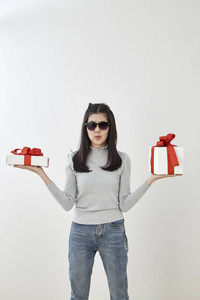 年轻的亚洲女性展示OK，礼品盒装在明亮的灰色墙壁背景上