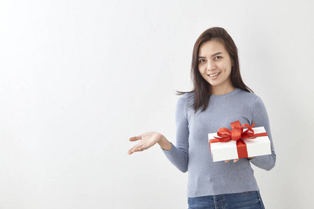 年轻的亚洲女性展示OK，礼品盒装在明亮的灰色墙壁背景上