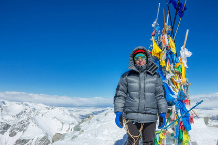 女登山者头盔和羽绒服与徒步杖站在山顶