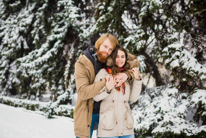 恋夫妇在一个冬天的公园里有一个约会,背景是一只雪母牛站在一个拥抱