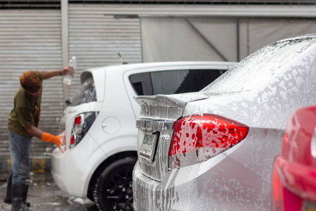 洗车。 男工清洗车使用高压水。 汽车护理服务商店。