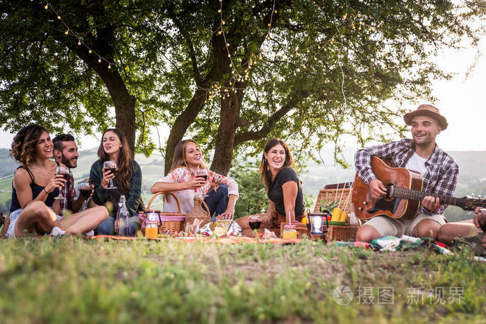 一群年轻快乐的朋友,在乡下的一个烧烤聚会上,在户外野餐,人们一边玩