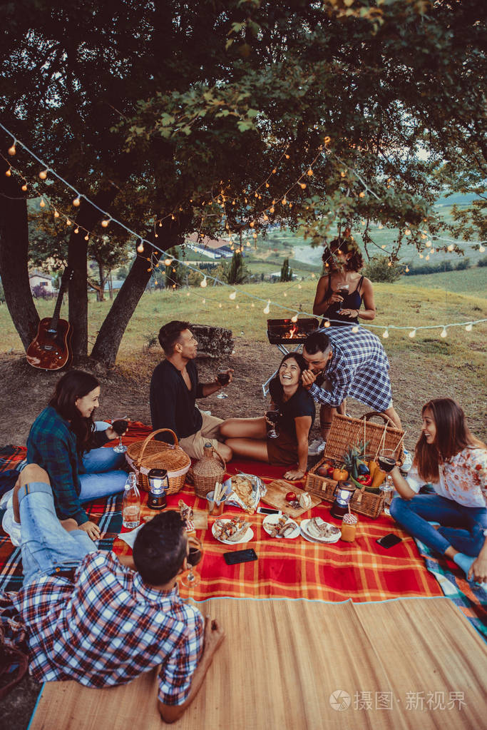 一群年轻快乐的朋友在乡下的一个烧烤聚会上在户外野餐人们一边玩一边