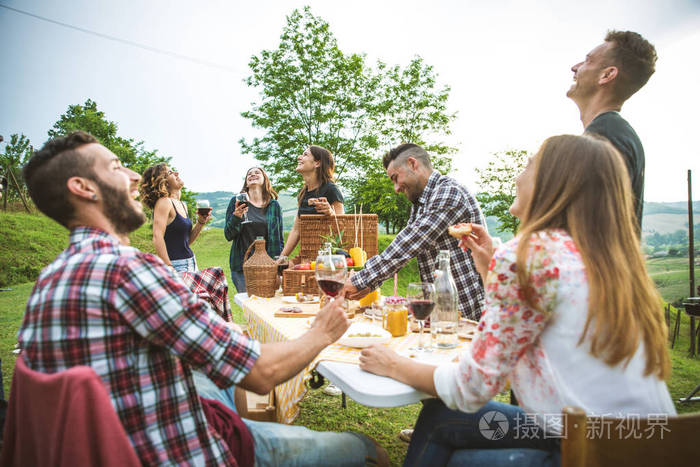 一群年轻快乐的朋友,在乡下的一个烧烤聚会上,在户外野餐,人们一边玩