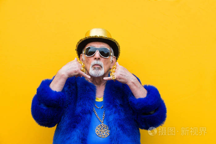 在60多岁的年轻老人身上摆着彩色背景的滑稽和奢侈的