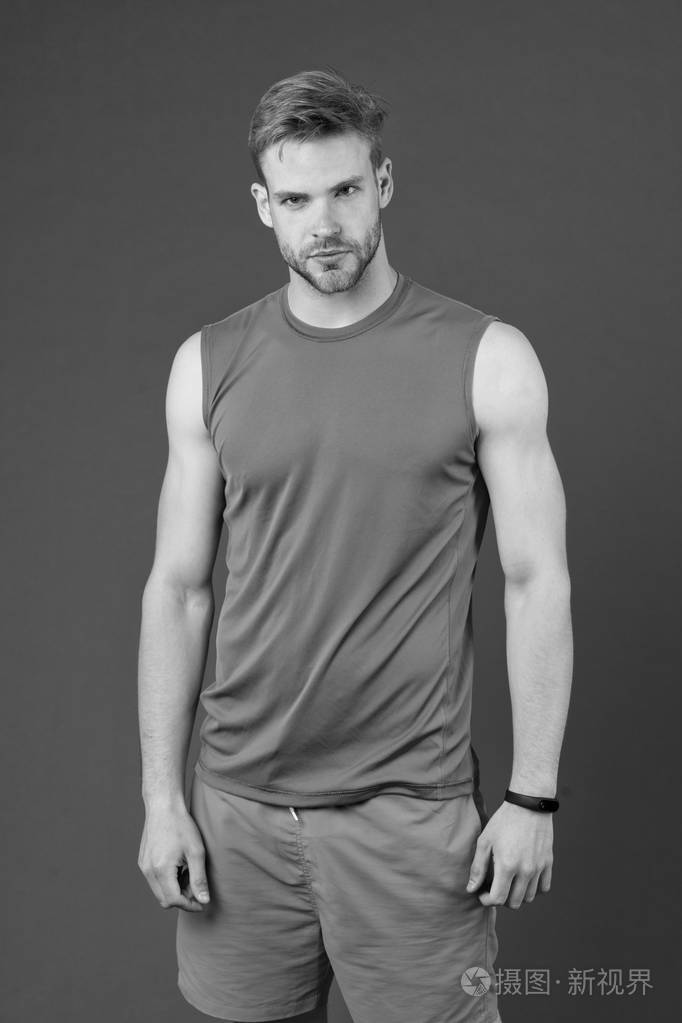 运动员在紫罗兰色背景.穿着橙色背心和蓝色短裤的肌肉发达的男人.