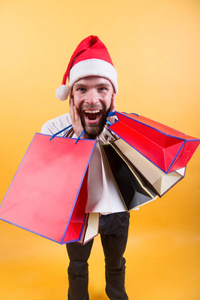 网上购物。新年快乐。圣诞节前的第二天早上快乐的圣诞老人在黄色背景。戴着圣诞老人帽子的人拿着圣诞礼物。送圣诞礼物。寒假销售
