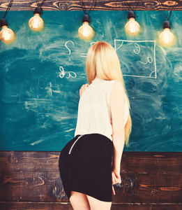 夫人老师在短的裙子与拉链在后面解释惯例。臀部漂亮的女人教数学。数学老师在黑板上写字, 后面看。教师理念