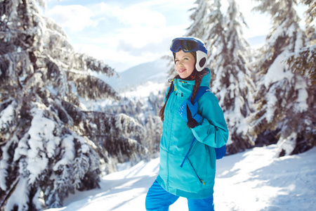 一个冬天穿着蓝色头盔和绿色夹克的漂亮女孩正在山里玩得很开心。 旅游休闲自由运动的概念。 美丽的自然会带来好天气。
