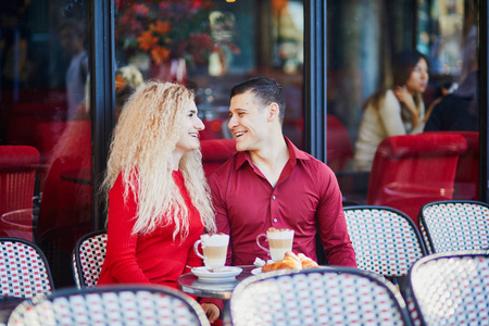 巴黎户外咖啡馆的美丽浪漫情侣。 法国巴黎餐馆的游客喝咖啡吃牛角面包