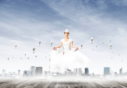 穿着白色衣服的女人闭上眼睛，集中注意力，一边沉思着云彩，一边欣赏城市风景，一边在背景上放飞气球。