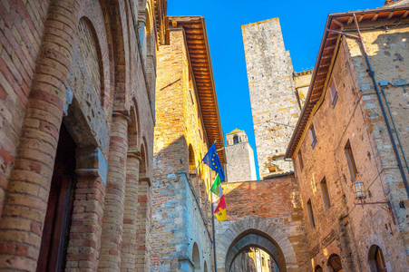 圣吉米尼亚诺老城建筑和塔楼的全景，悬挂着意大利和欧盟的旗帜。 意大利托斯卡纳。
