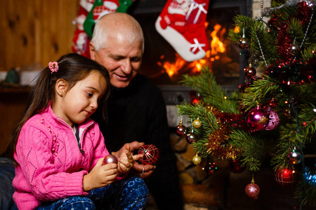 祖父在圣诞树附近的圣诞节室内玩孙女