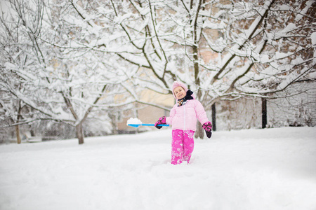 这个孩子在冬天玩雪。 一个穿着明亮夹克和针织帽子的小女孩在一个冬天的公园里为圣诞节捕捉雪花。 孩子们在白雪覆盖的花园里玩耍和跳跃