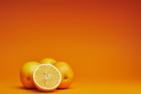 在橙色背景下近距离观看新鲜成熟的整体和切片的橙子