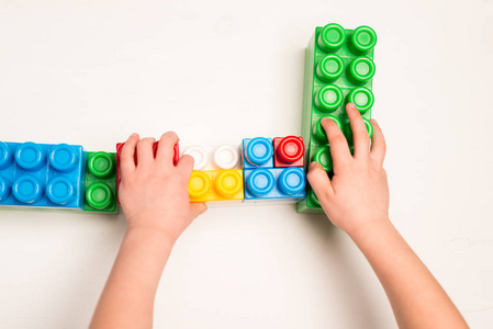 s hands playing with colorful plastic bricks