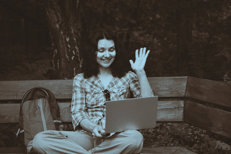 在公园里用笔记本电脑旅行的女人。从事自然工作的自由职业概念