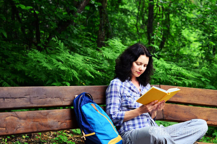 旅行的女人看书,在公园放松.假期自由工作和学习的概念