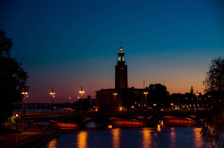 斯德哥尔摩市政厅Stadshuset市政委员会大楼，昆肖门岛诺贝尔奖，桥，马勒伦湖的路灯反射在惊人的日落，黄昏，黄昏，瑞典