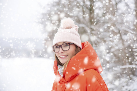 特写中年妇女戴帽子的肖像，站在户外，享受冬天的天气。