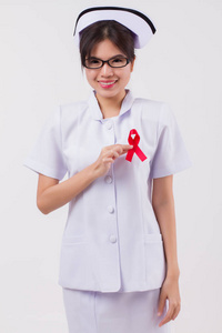 女护士手拿红丝带弓艾滋病毒或艾滋病意识符号，由妇女在演播室拍摄。 医疗慈善护士基金筹款概念红丝带艾滋病日宣传