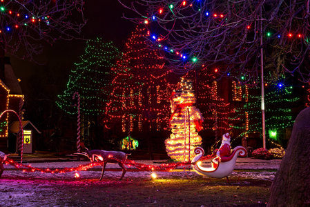 一个穿着雪橇驯鹿的圣诞老人一个巨大的雪人和一个圣诞场景是一个乡村广场上节日户外圣诞展示的一部分